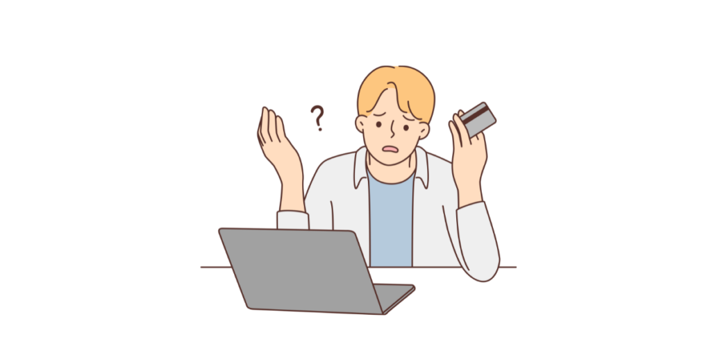 クレジットカードを手にしてパソコンの前で困っている男性